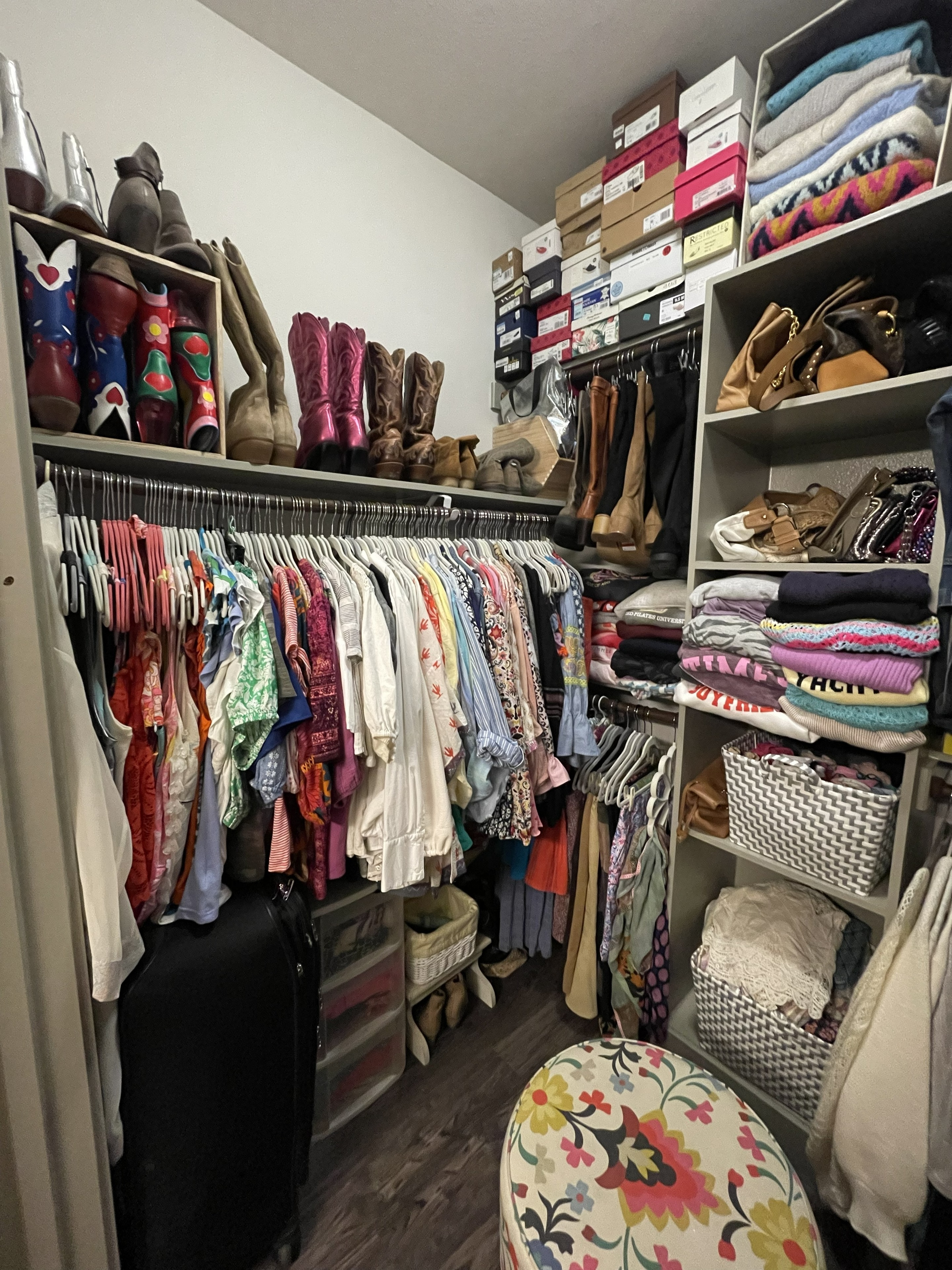 Organized closet with center shelving unit, boots, and handbags
