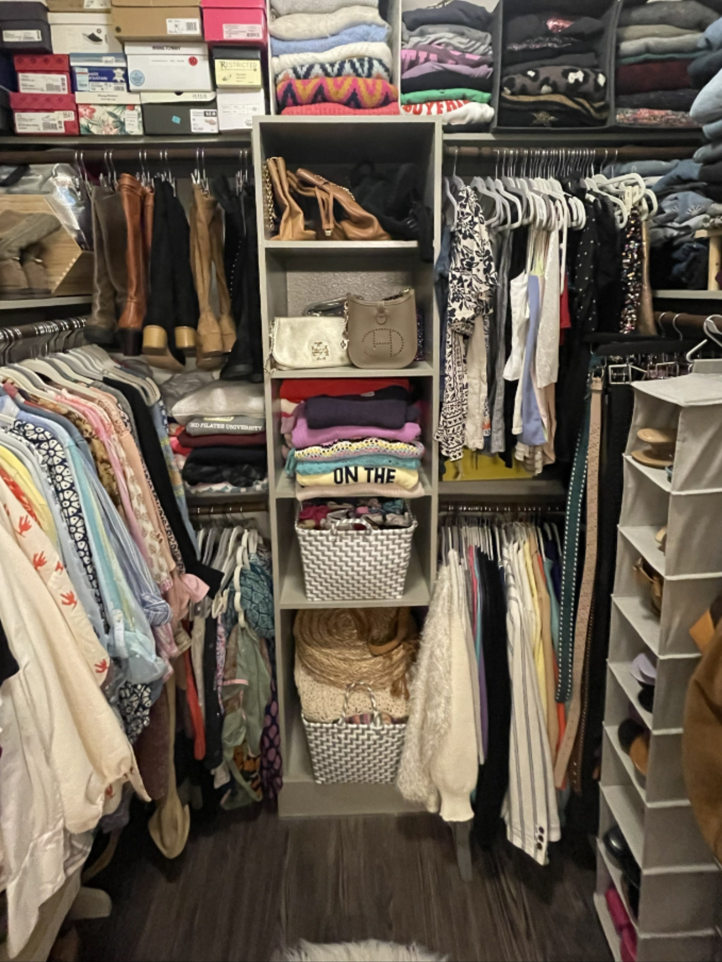 Organized walk-in closet with boots on shelf and floral stool