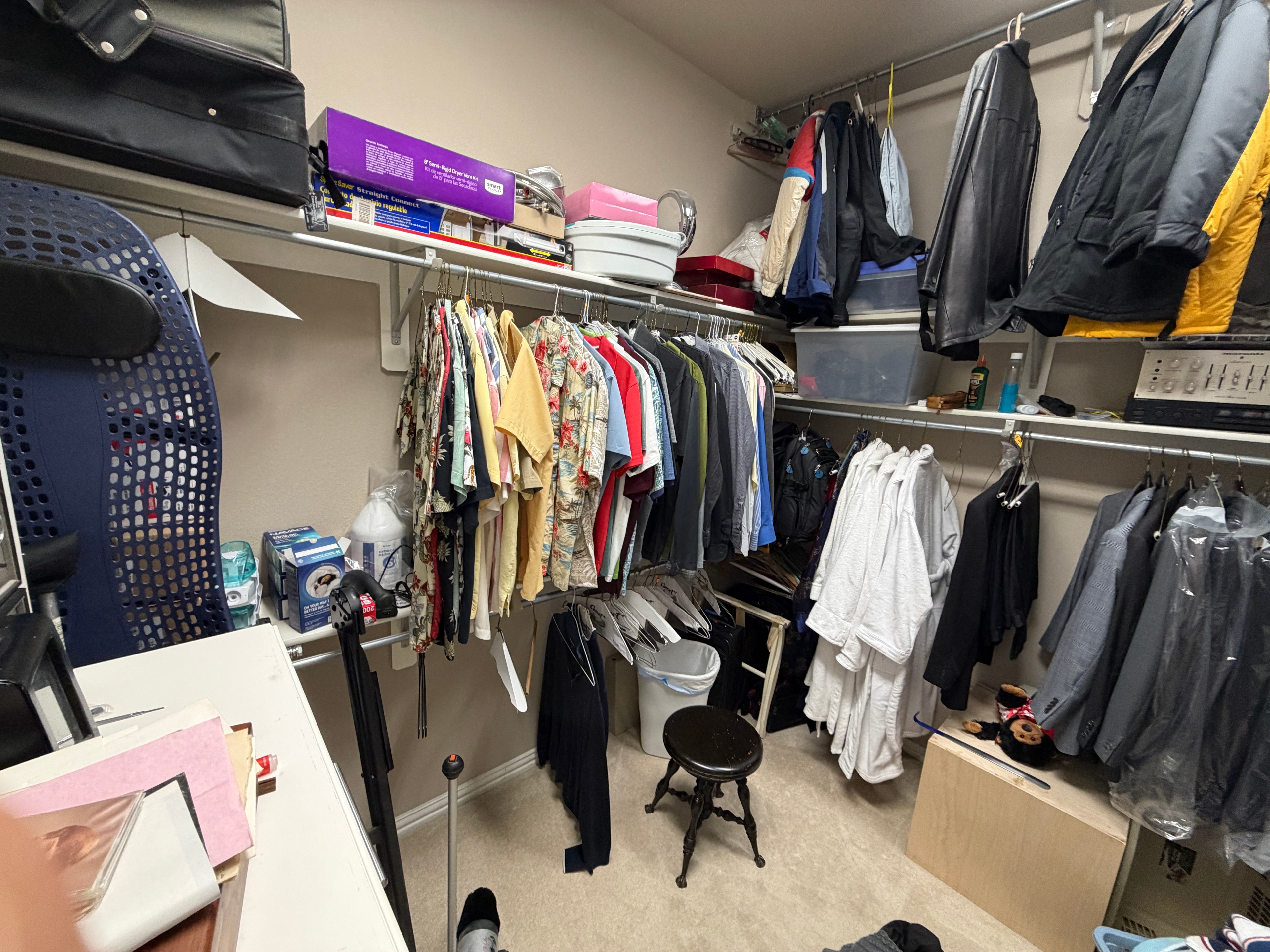 Cluttered closet with overfull clothing racks and miscellaneous items