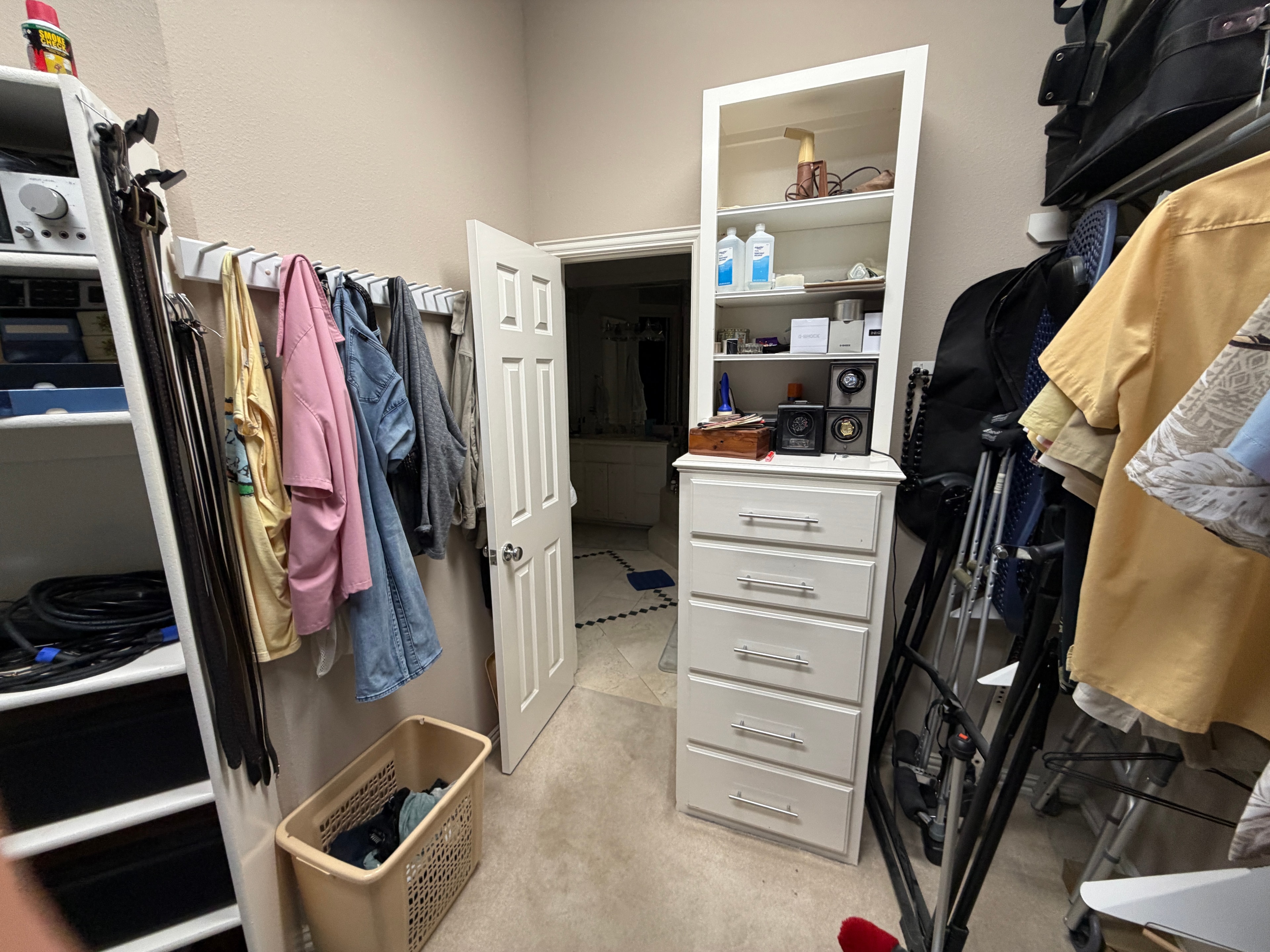 Closet doorway area with belts, jackets, and a dresser crowded with items
